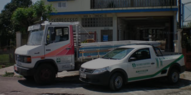 Caminhão e Saveiro em frente ao prédio de dois andares. na faixada escrito Cedrogesso.